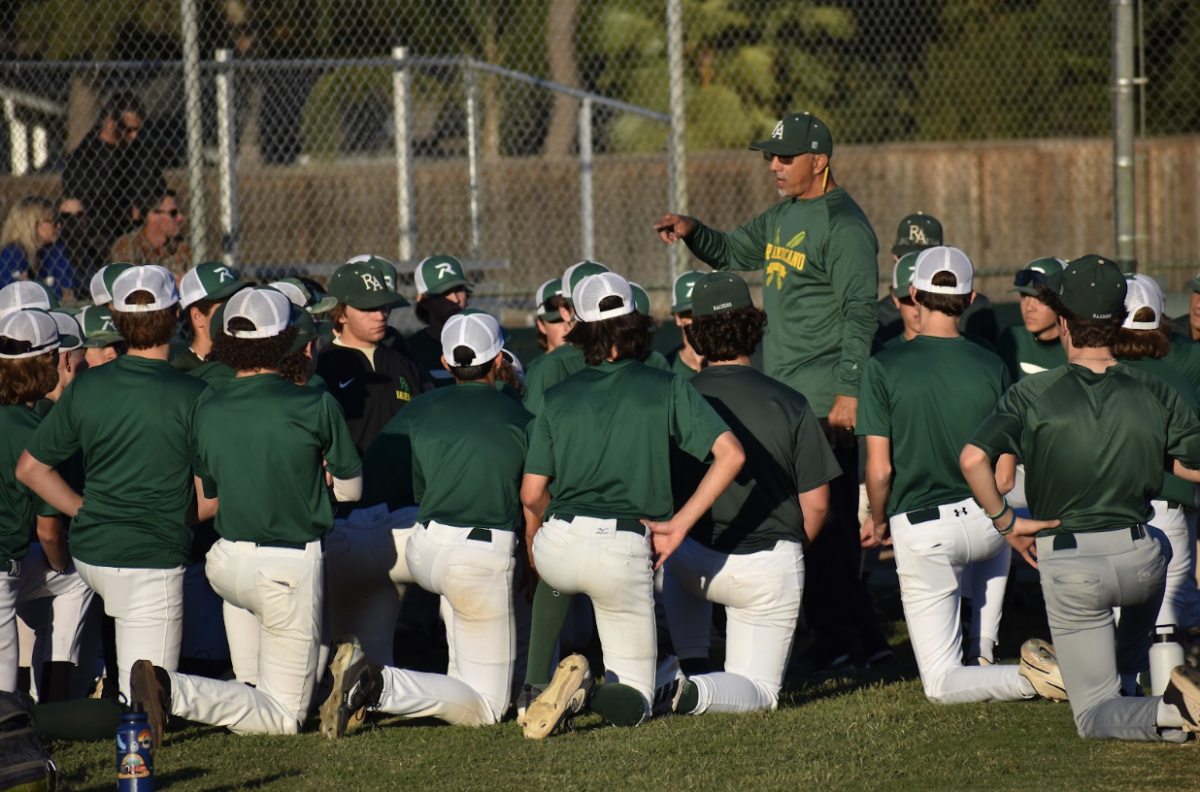 The varsity baseball team takes a knee for a pregame talk.